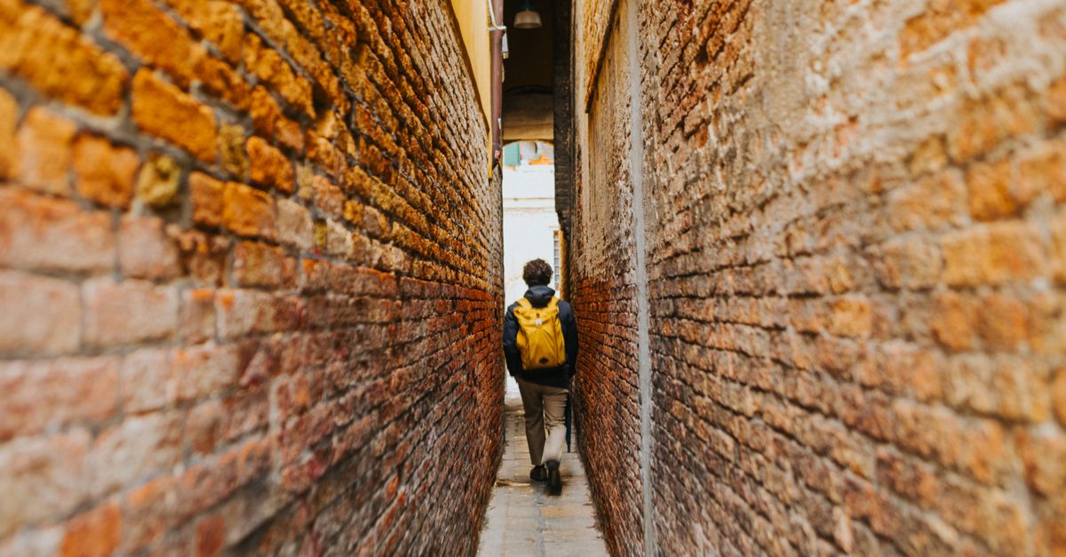 A solo traveler with a backpack checking a map on a quiet old-town street.