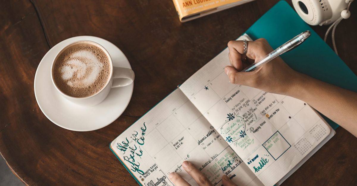 An open notebook with a handwritten agenda and three coffee cups.