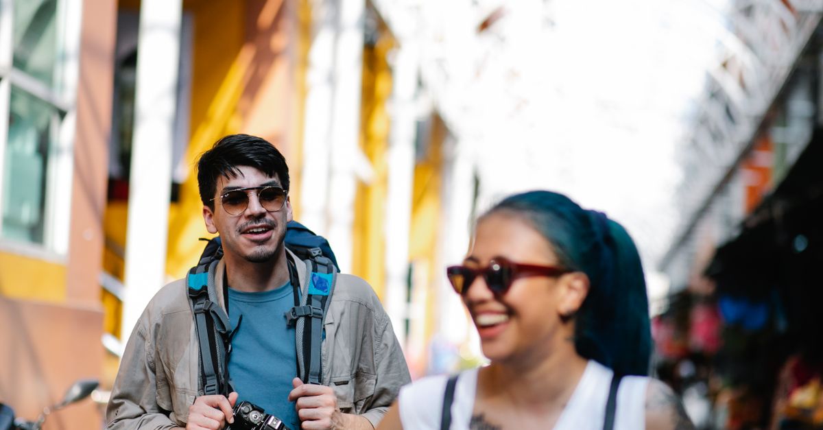 Friends walking through an old town street with backpacks, laughing.