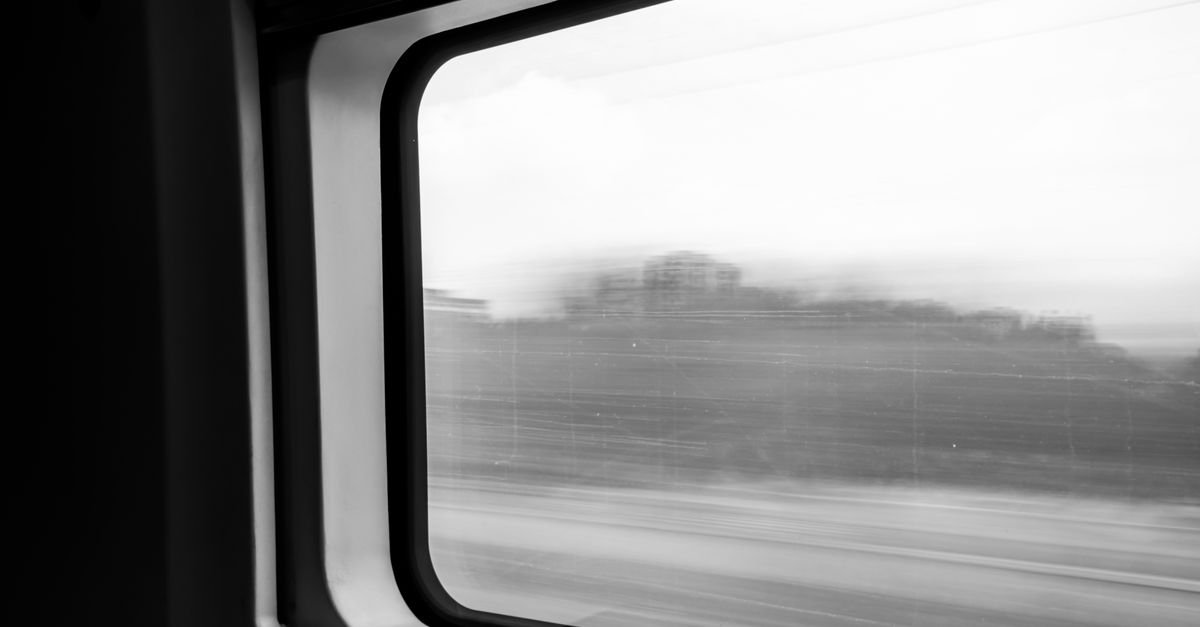 A train window view of landscapes passing between two destinations.