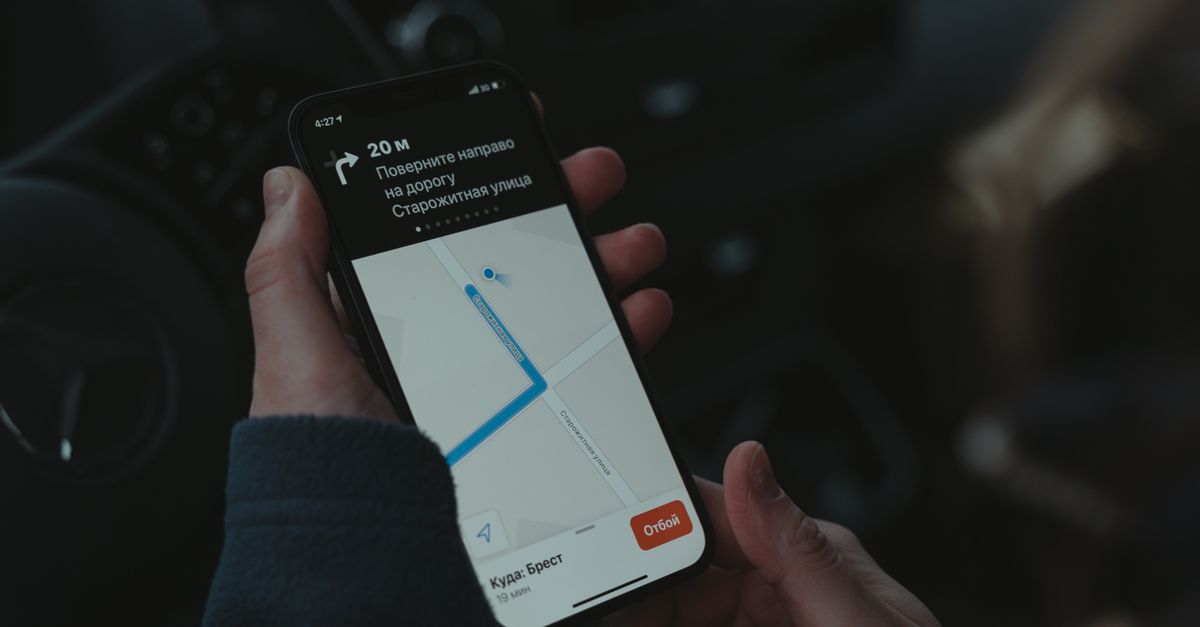 A weather app showing a rain forecast on a phone held over a paper map.